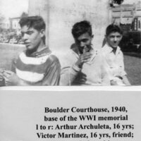 Three teen-aged boys sitting on base of WWI memorial